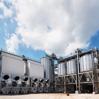 Agricultural Silos. Building Exterior. Storage and drying of grains, wheat, corn, soy, sunflower against the blue sky with white clouds.